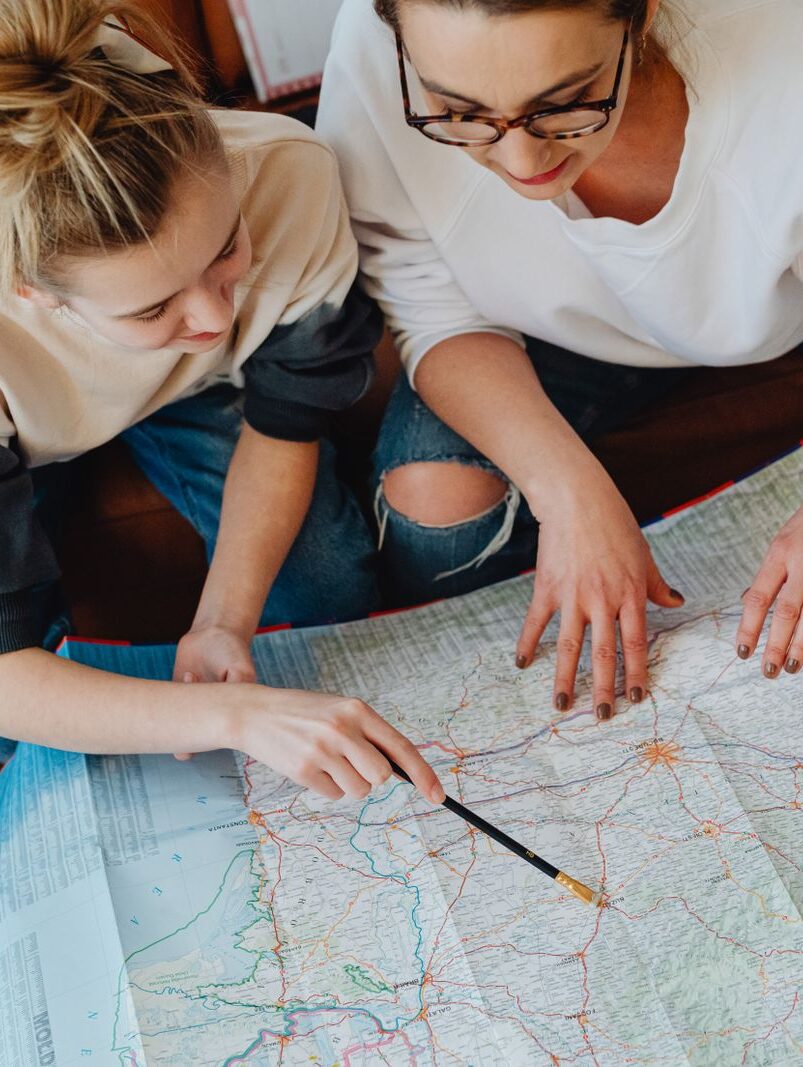 A mother and daughter plan their journey using a map, symbolizing adventure and bonding.